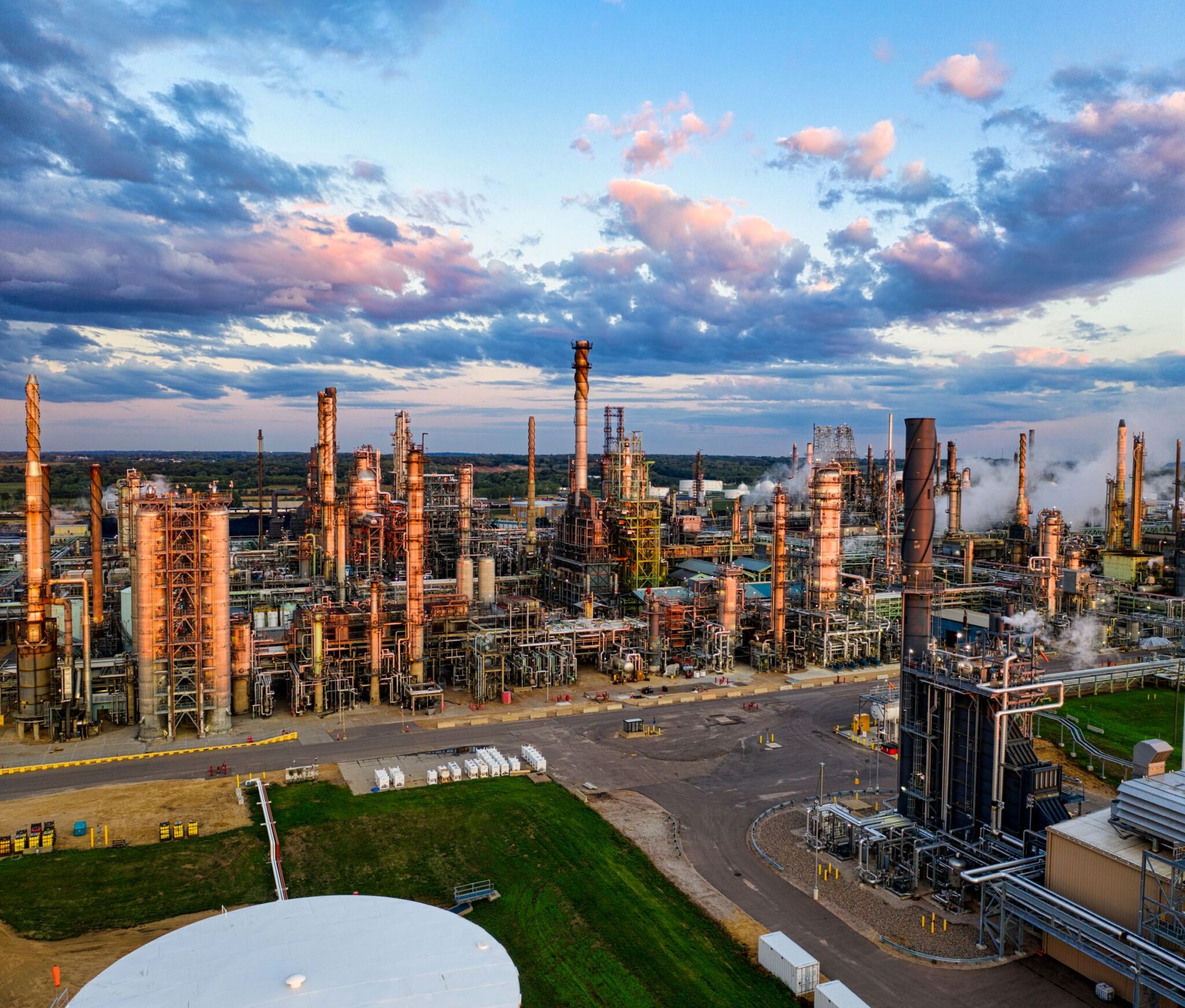 Aerial view of a refinery and syngas complex at dusk, showing fired heater boxes, stacks and distillation columns