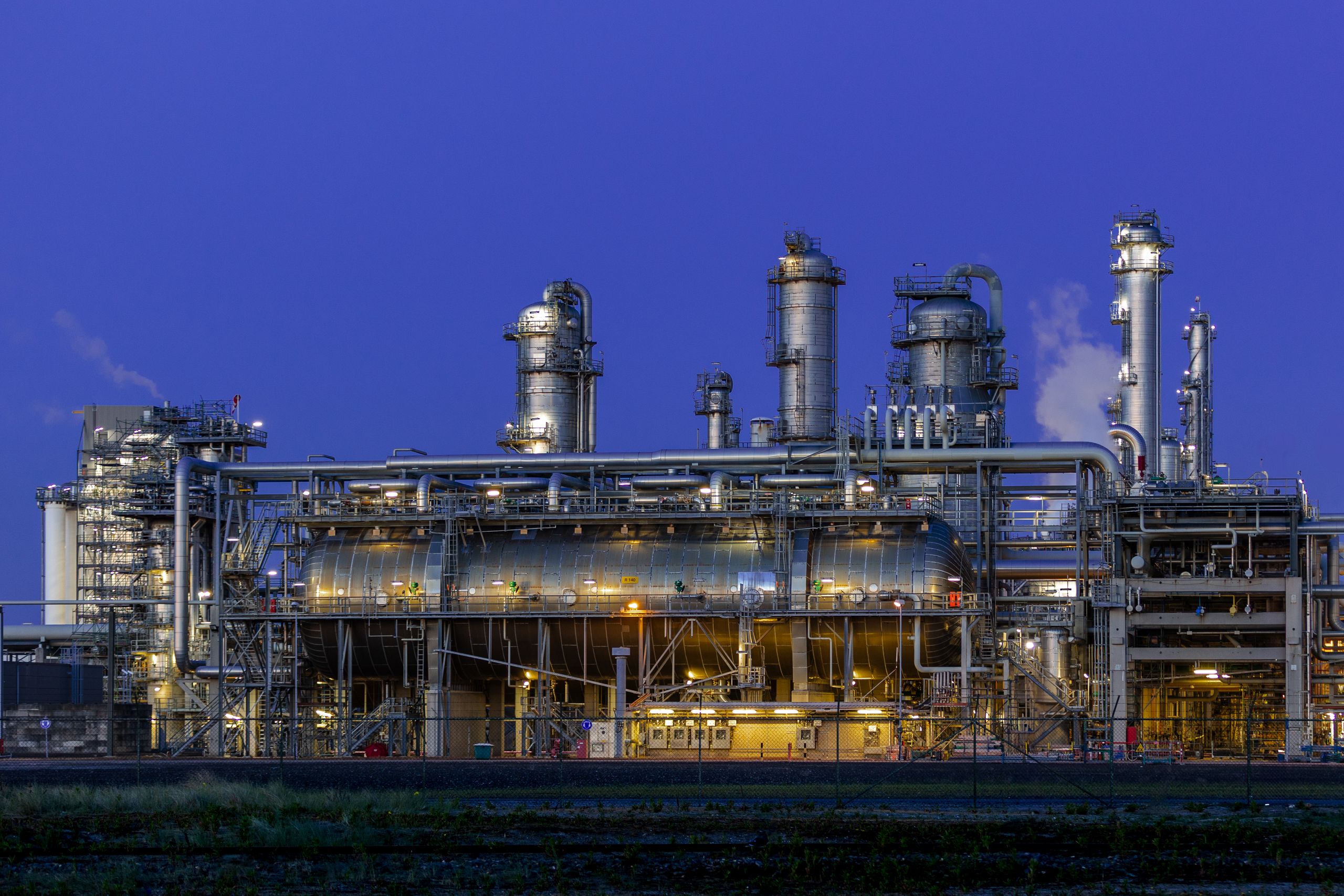 Natural gas processing and syngas plant illuminated at night, showing reformer, columns and heat-recovery equipment